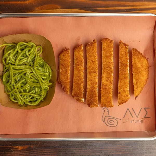 Peruvian green spaghetti and breaded fish sticks on a brown paper-lined tray from Ave By Divino.