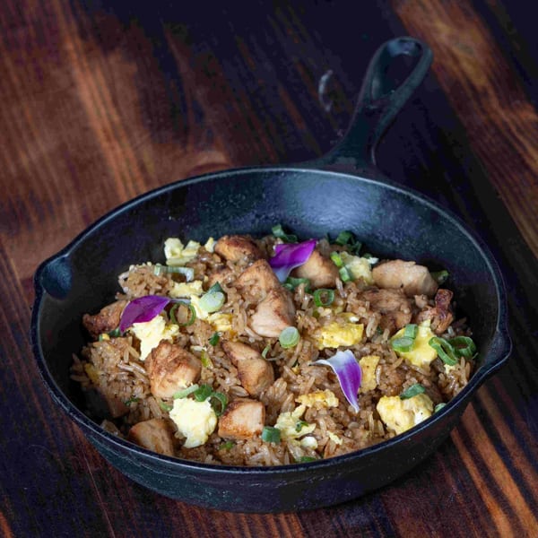 Peruvian arroz chaufa with chicken, scrambled egg, and green onions in a cast iron pan.