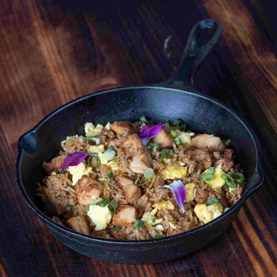 Peruvian arroz chaufa with chicken, scrambled egg, and green onions in a cast iron pan.